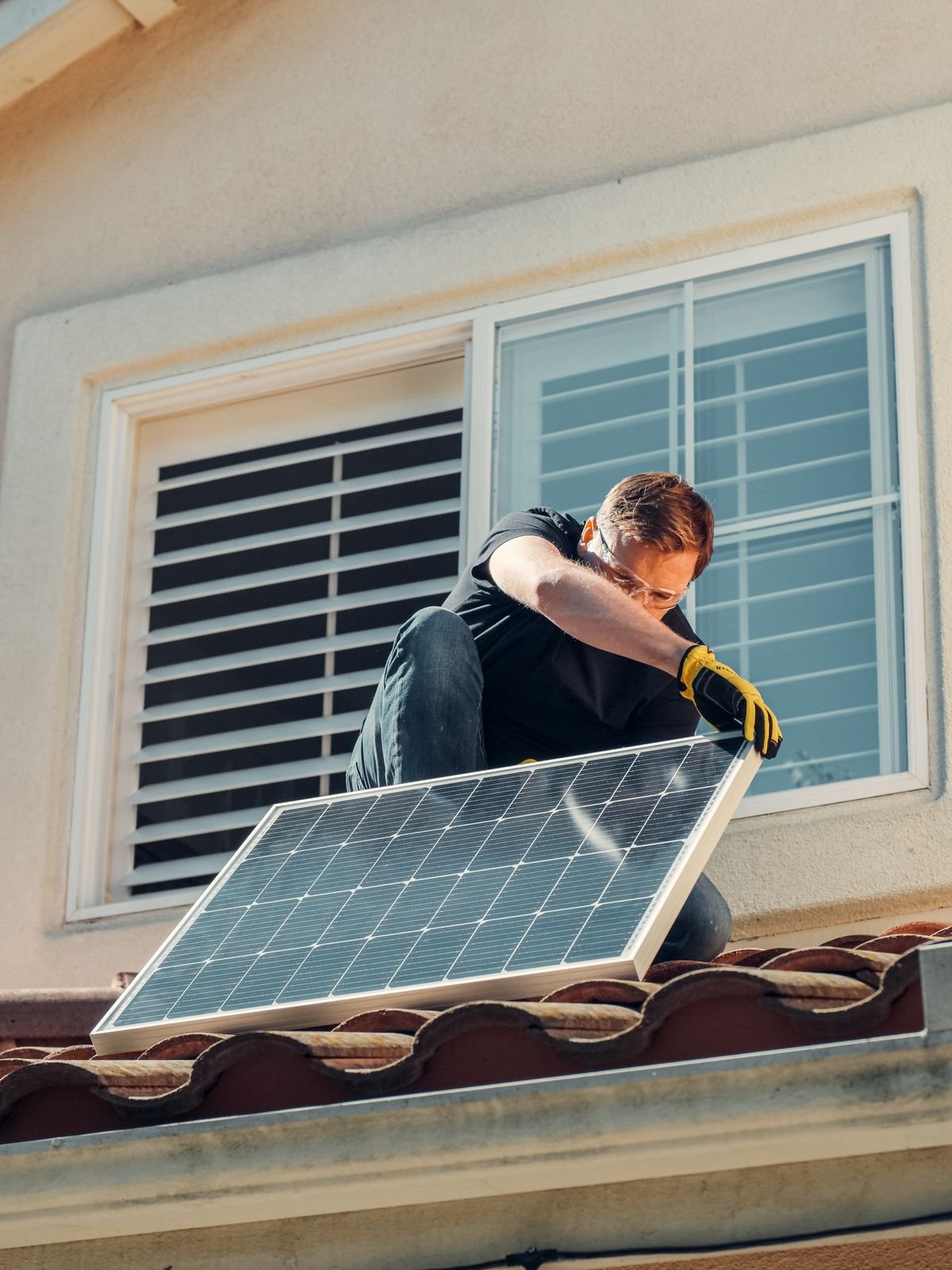 Solar installer mounting a solar panel on a rooftop